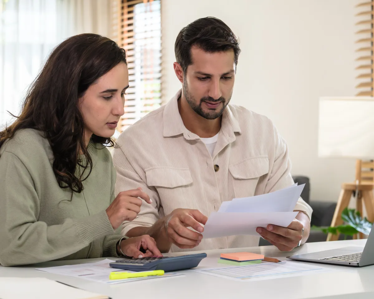 Couple reviewing financing options with a calculator and laptop at home