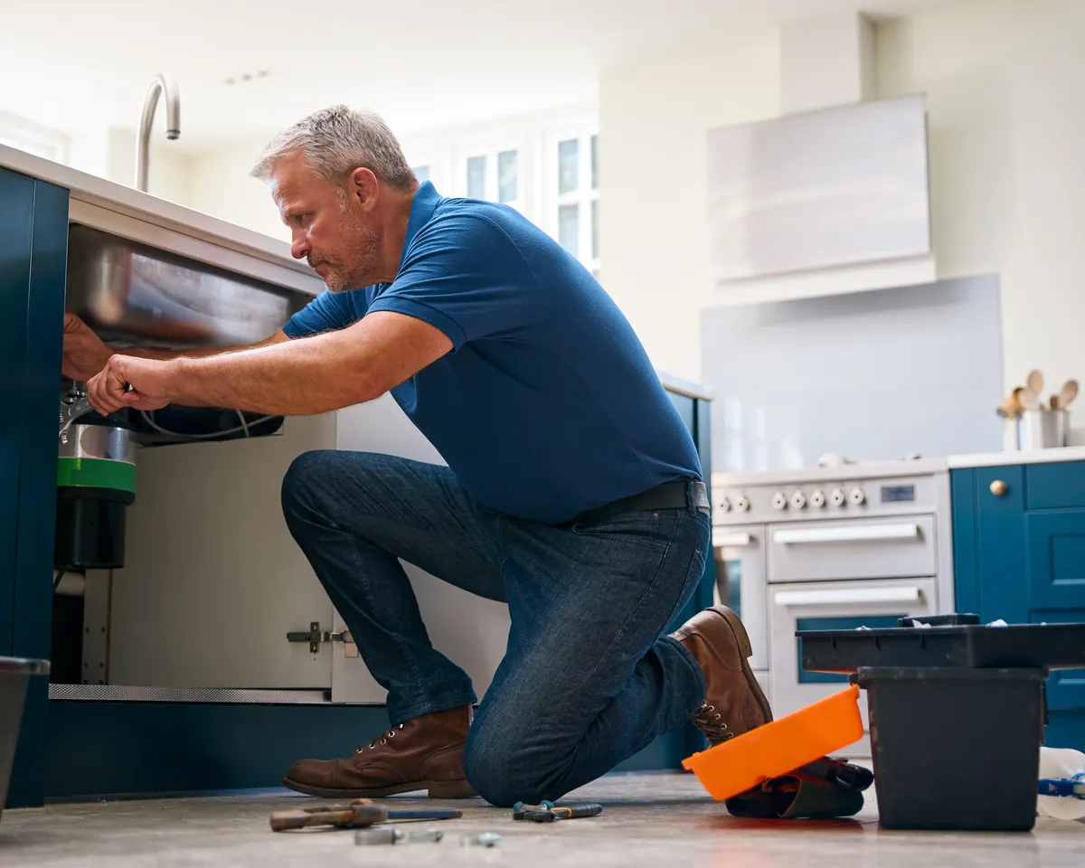Licensed plumber repairing a kitchen sink in a Houston home