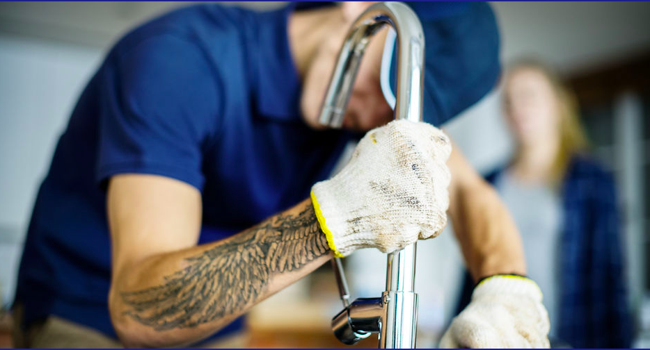 A plumbing working on a sink fixing a faucet.