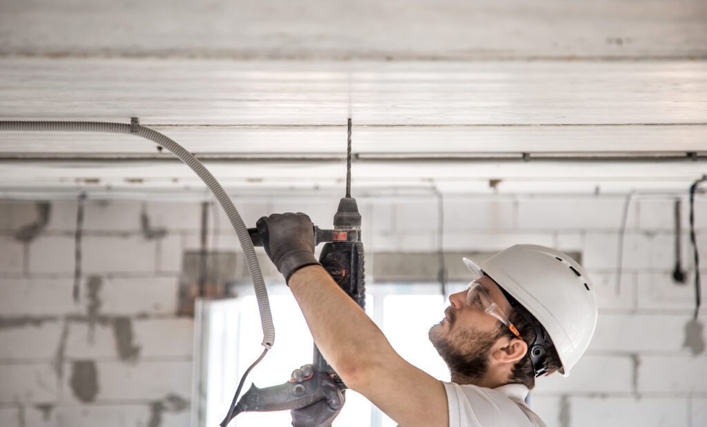 Handyman uses jackhammer, for installation, professional worker on the construction site. The concept of electrician and handyman.